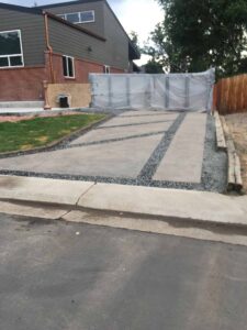 Residential concrete driveway divided by dark decorative stone strips