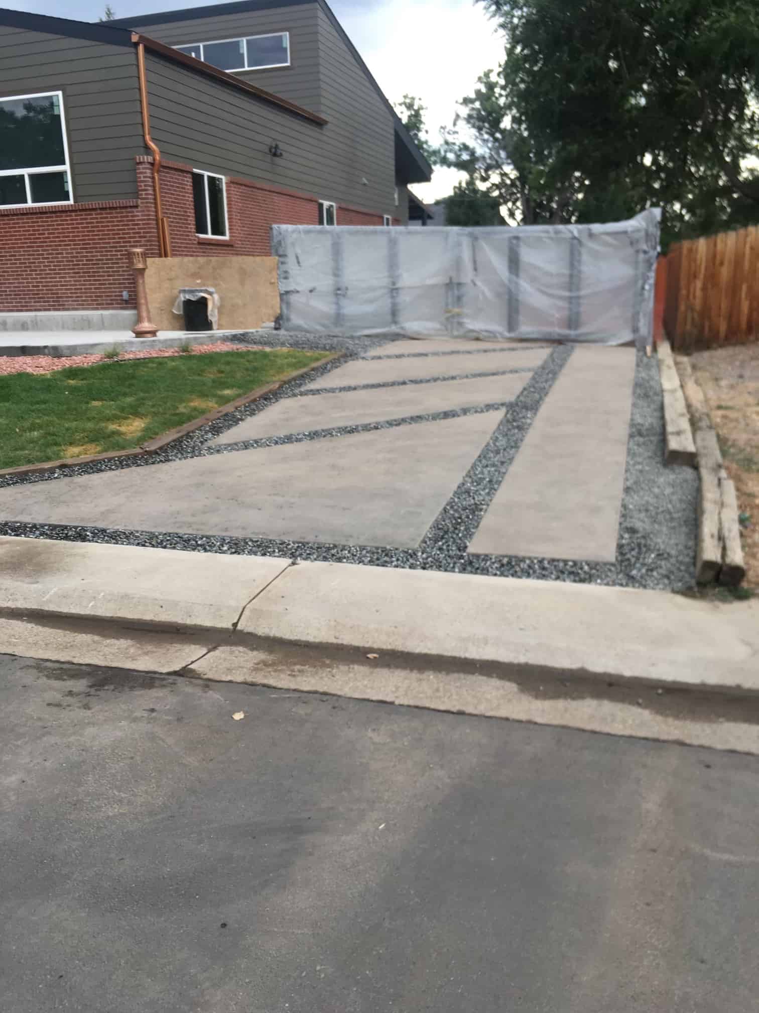 Residential concrete driveway divided by dark decorative stone strips