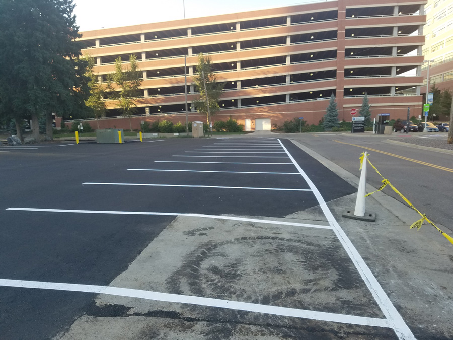 Striped asphalt parking lot beside a multistory parking structure