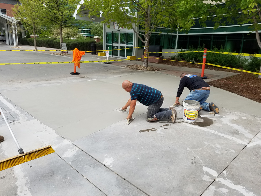 Crew finishing a concrete surface outside a commercial building