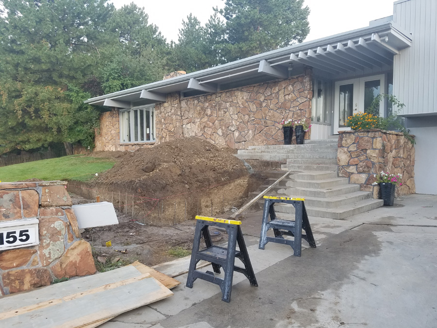 Concrete entry and driveway work in progress outside a stone-front home