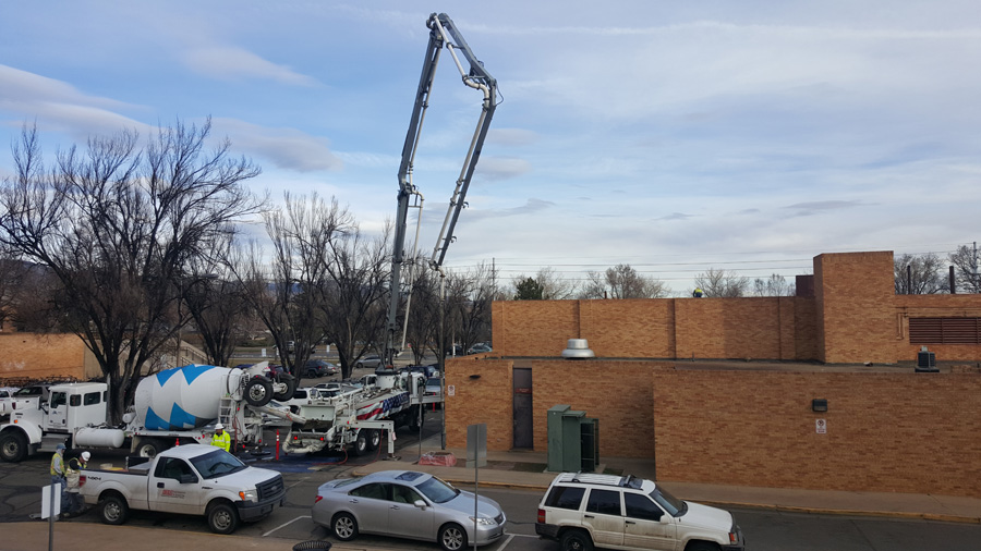 Concrete pump truck operating beside a brick building
