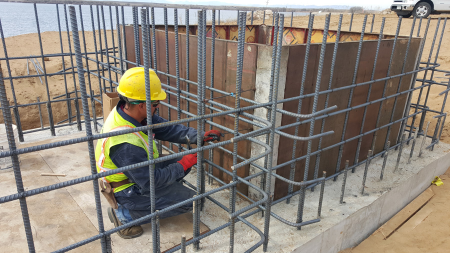 Worker assembling a grid of steel reinforcement for a concrete wall