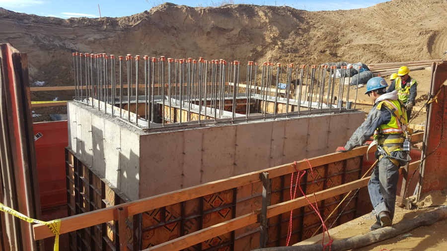 Concrete wall formwork with workers alongside a prepared site