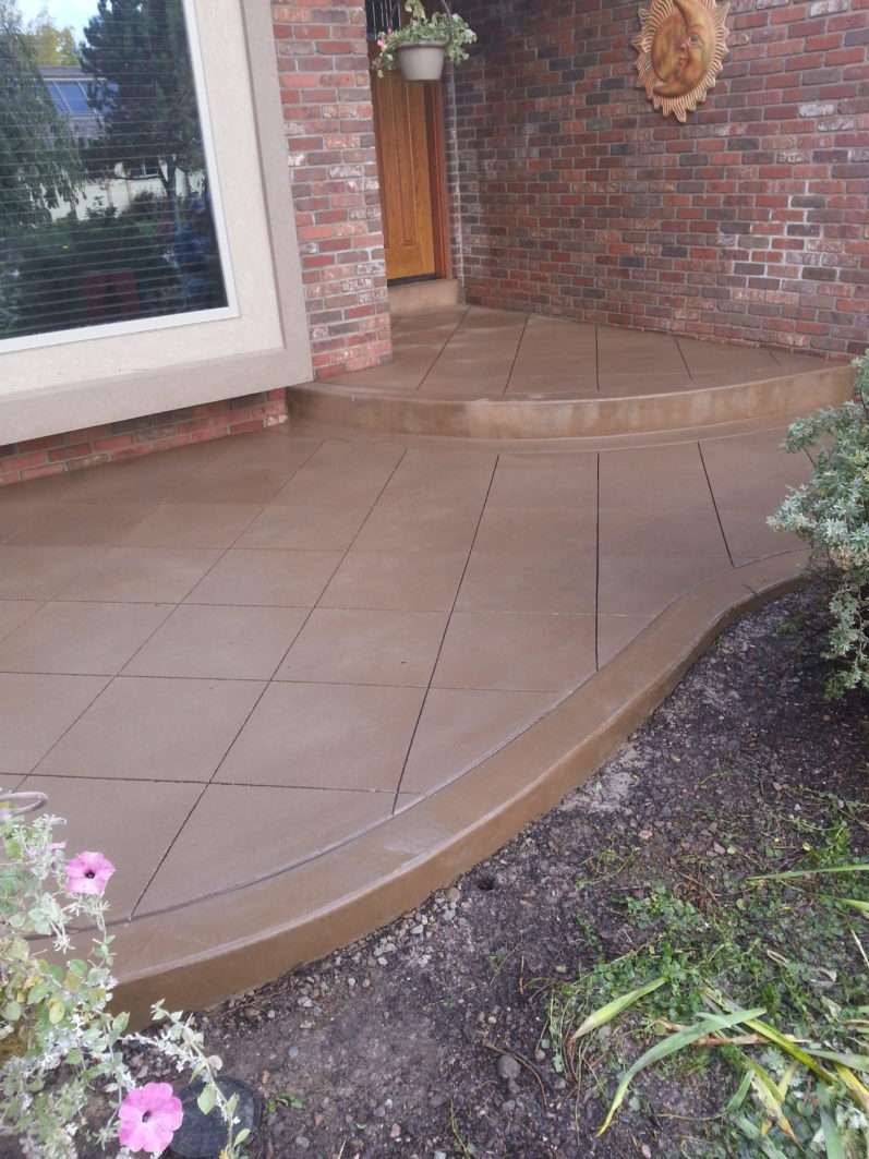 Curved colored concrete patio outside a brick home
