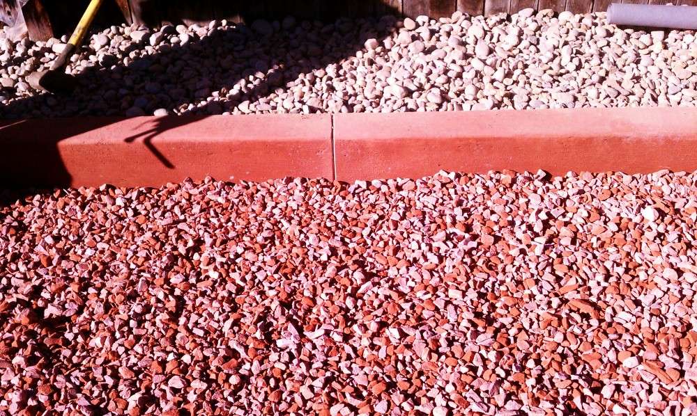 Colored concrete garden edging beside a bed of decorative stone