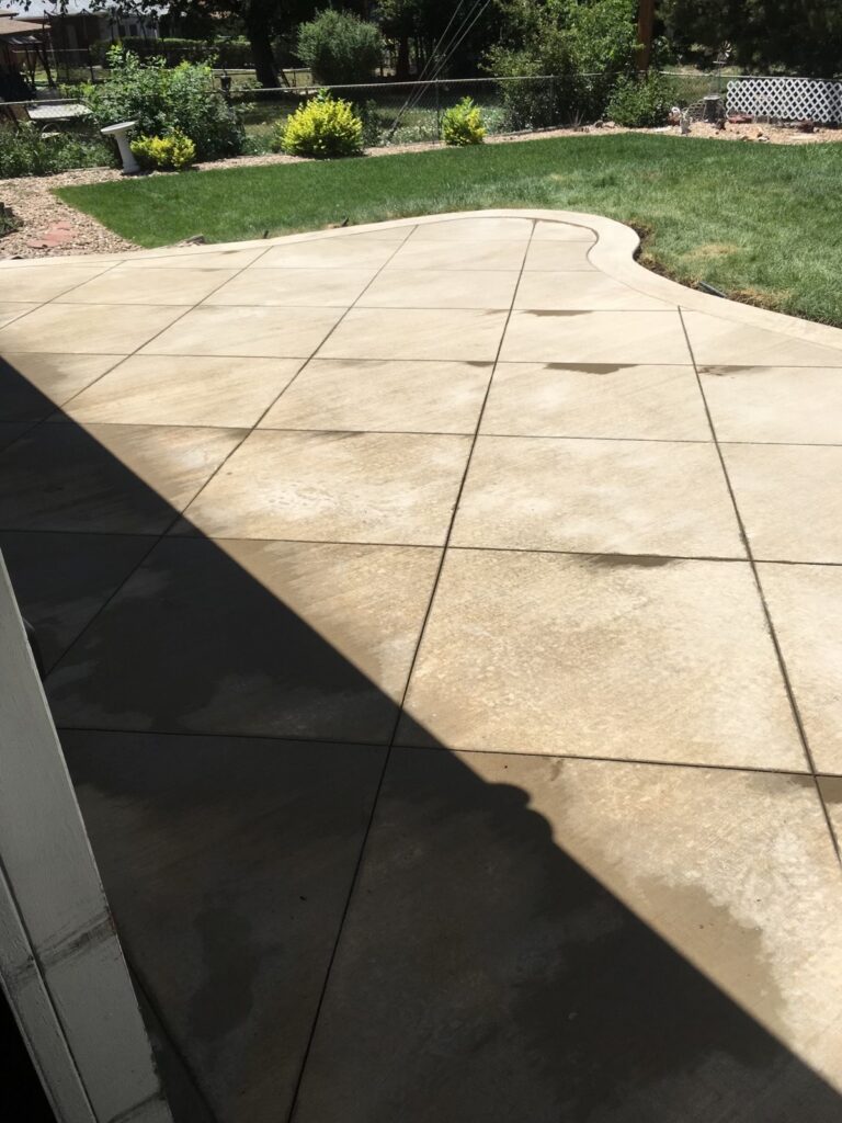 Concrete backyard patio with a joint pattern beside a lawn